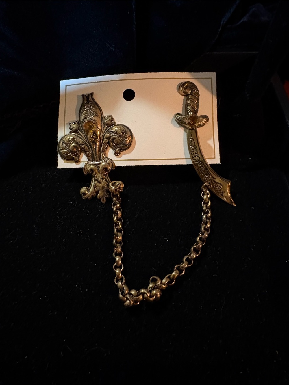 Vintage gold-tone fleur-de-lis and saber double pin connected by swag chain.